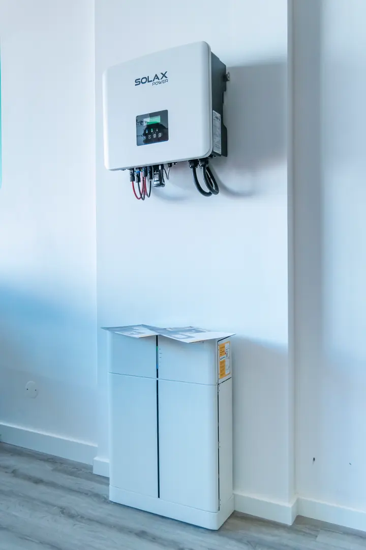 Inversor e bateria de armazenamento de energia numa parede branca.